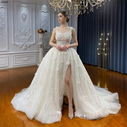 Full-length view of an elegant strappy beach wedding dress featuring a high thigh slit and shimmering floral lace.