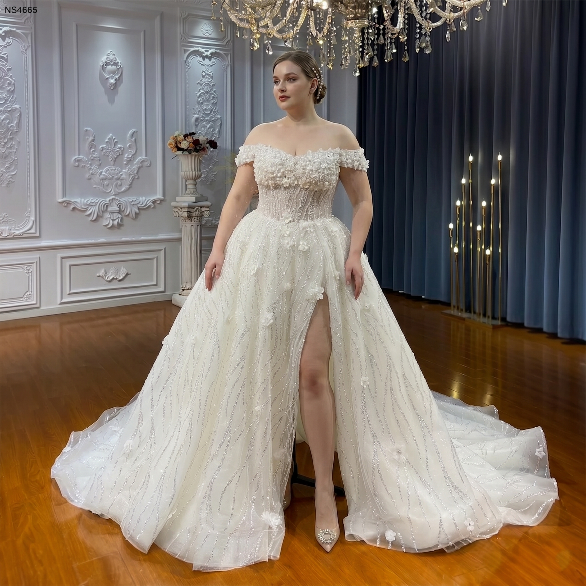 Plus-size bride wearing a romantic strappy bridal gown with a dramatic skirt slit and 3D floral appliqués.