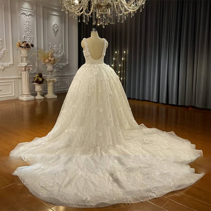 Back view of a beach wedding gown highlighting a deep U-back, delicate straps, and an expansive sparkling train.