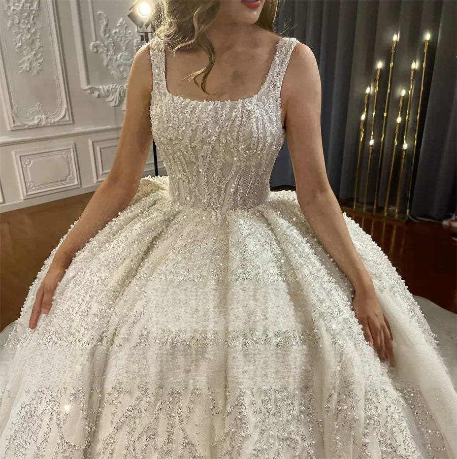 Close-up detail of a luxury wedding dress bodice, showcasing the square neckline, thick straps, and exquisite vertical and branch-like silver crystal beadwork.