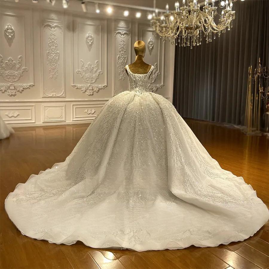 Breathtaking back view of a luxury ball gown wedding dress on a mannequin, emphasizing the wide, shimmering cathedral-length train adorned with intricate silver crystal branch patterns.