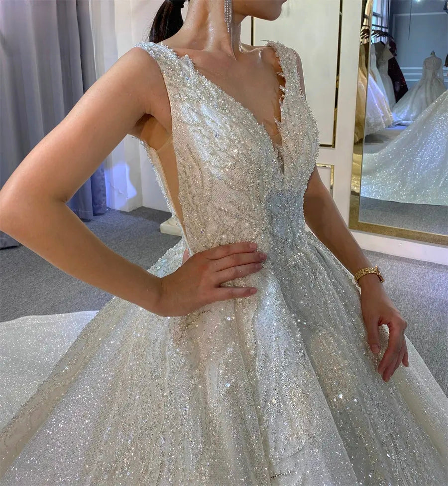 Close-up detail of the shimmering bridal gown bodice, highlighting the intricate sparkling patterns, delicate straps, and elegant V-neck design.