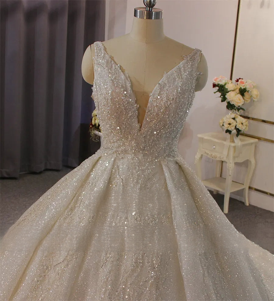 Detailed close-up of the plunging V-neckline and sparkly fabric texture on a luxury sleeveless ball gown wedding dress.