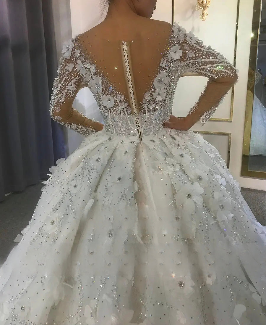 Close-up back detail of the stunning off-white bridal gown, highlighting the sheer crystal-beaded V-back, 3D floral accents, and a traditional lace-up corset closure.