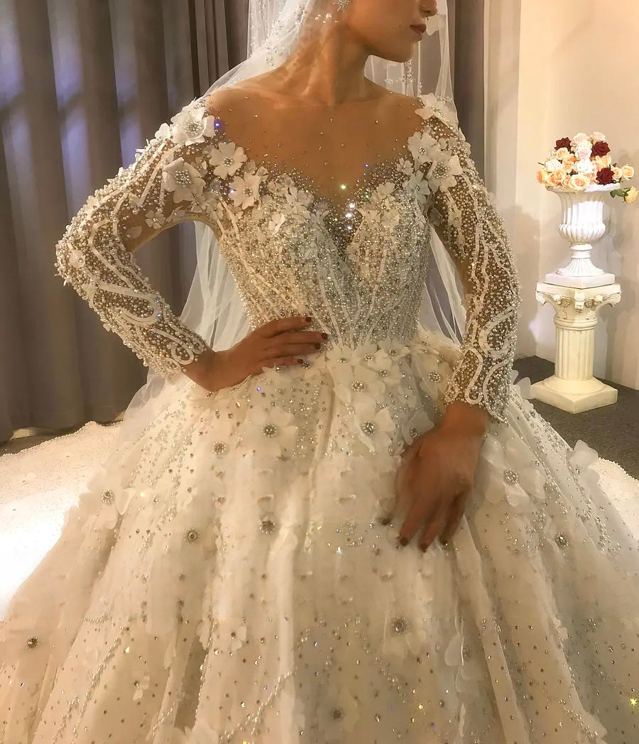 Detailed front close-up of the heavy beading and 3D floral appliqués on the bodice and long sleeves of this stunning off-white elegant wedding dress.