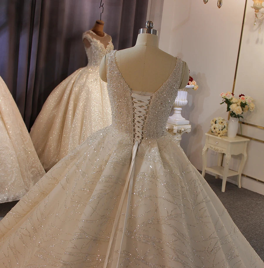 Close-up back view of a luxury sleeveless bridal gown, featuring an elegant lace-up corset and intricate beaded embellishments cascading down the voluminous skirt.