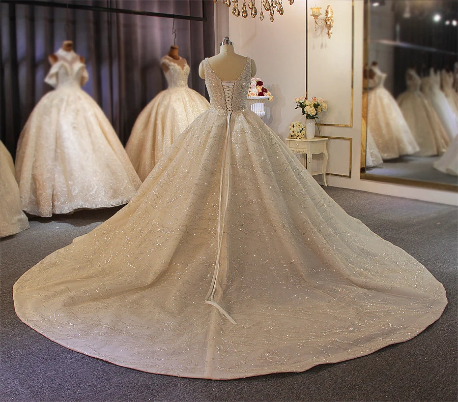 Dramatic full rear perspective of a luxury beaded ball gown wedding dress on a mannequin, showcasing the massive, shimmering cathedral-length train in a high-end boutique.