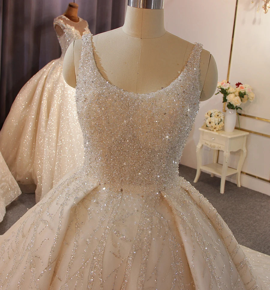 Detailed close-up of a sleeveless scoop-neck bridal bodice, highlighting the dense, sparkling hand-beaded embellishments and structural pleats of the luxury ball gown.
