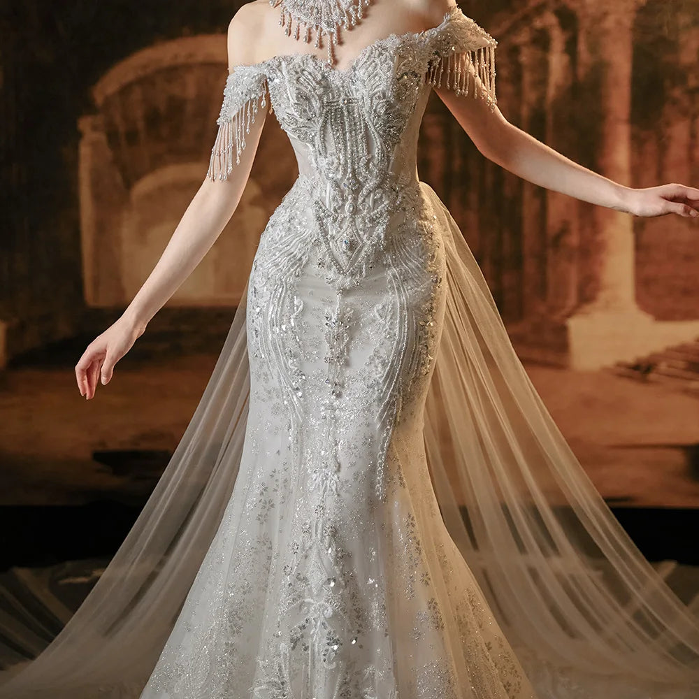 Close-up front detail of a luxury mermaid wedding dress bodice, highlighting the intricate hand-sewn silver beadwork, crystal patterns, and the unique off-the-shoulder beaded tassel sleeves.