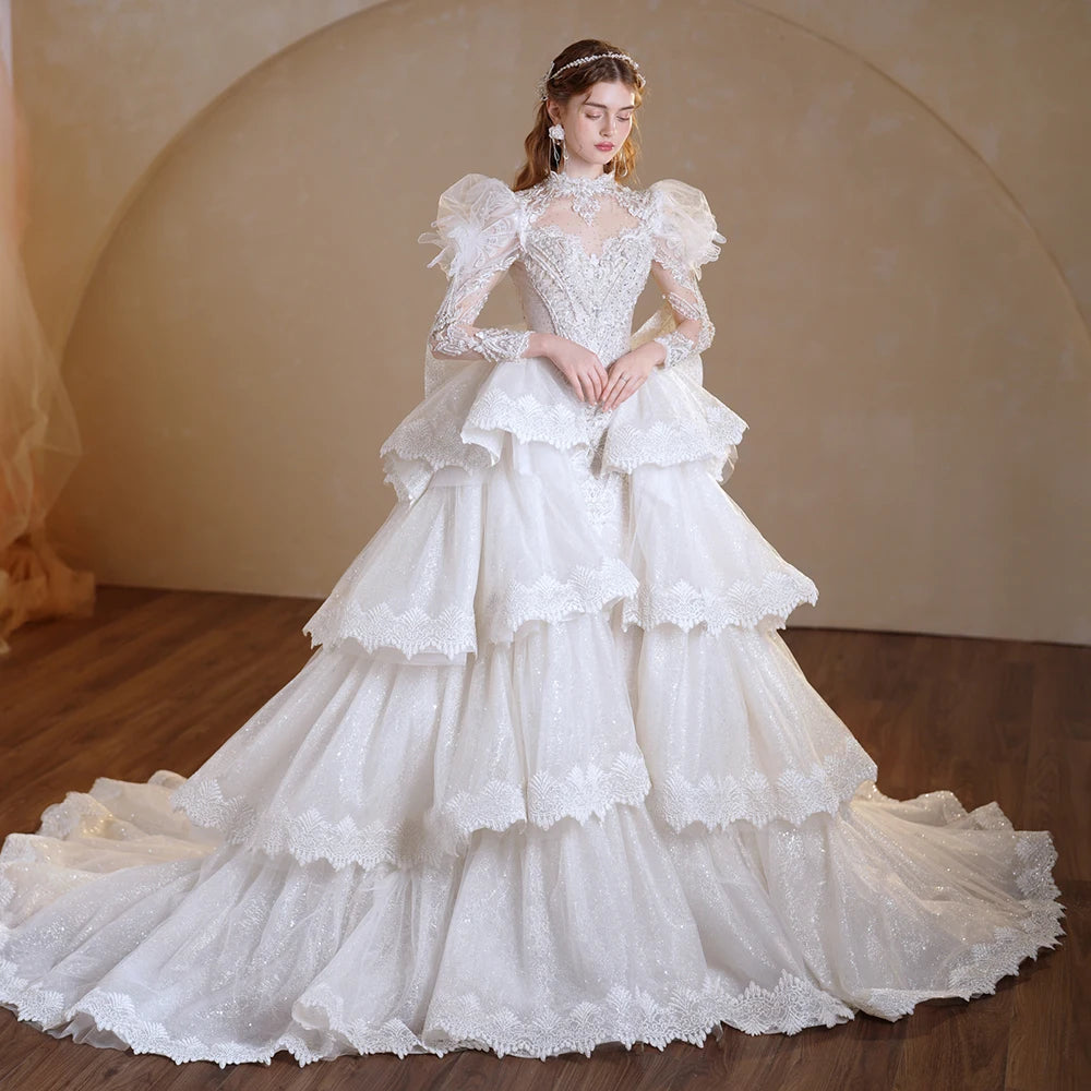 Full-length front view of an elegant model wearing a superfine O-neck full sleeve wedding dress featuring heavy sequin embellishments and a voluminous ball gown skirt under a crystal chandelier.