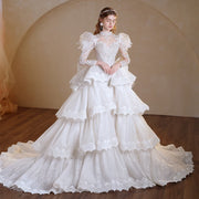 Full-length front view of an elegant model wearing a superfine O-neck full sleeve wedding dress featuring heavy sequin embellishments and a voluminous ball gown skirt under a crystal chandelier.
