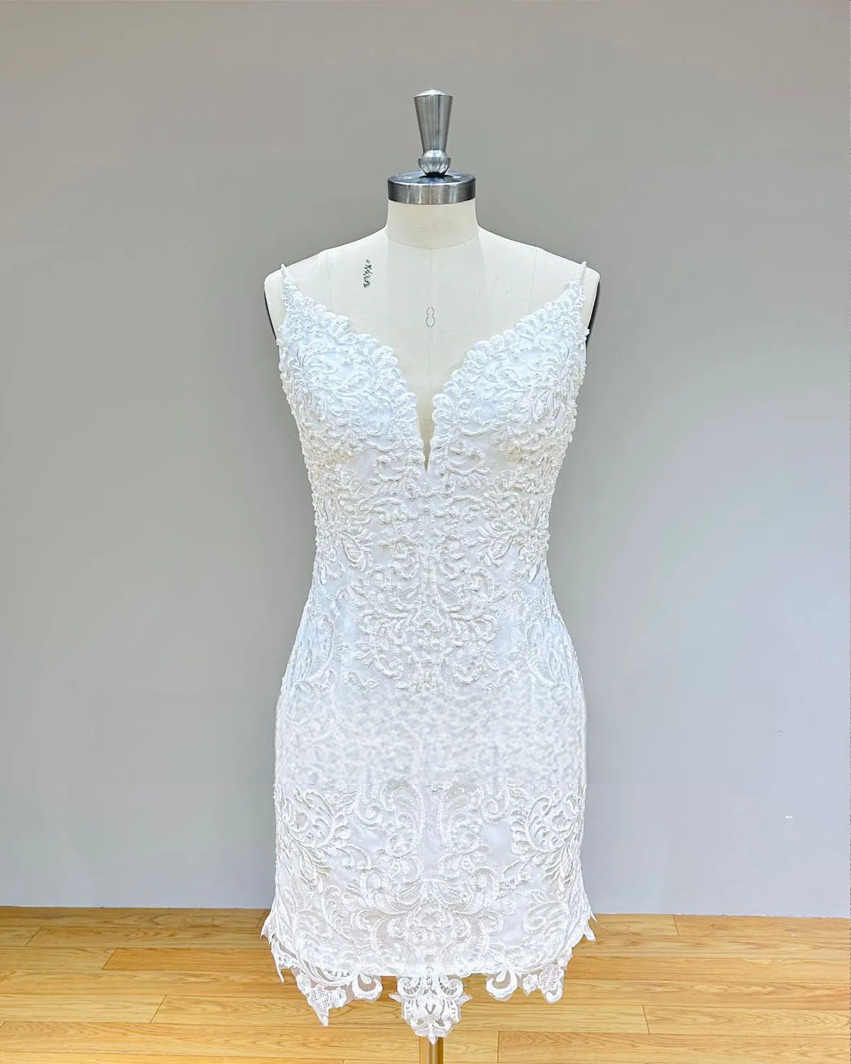 Detailed view of the short lace reception dress with thin straps and pearl beading, illustrating the versatile 2-in-1 detachable skirt feature.