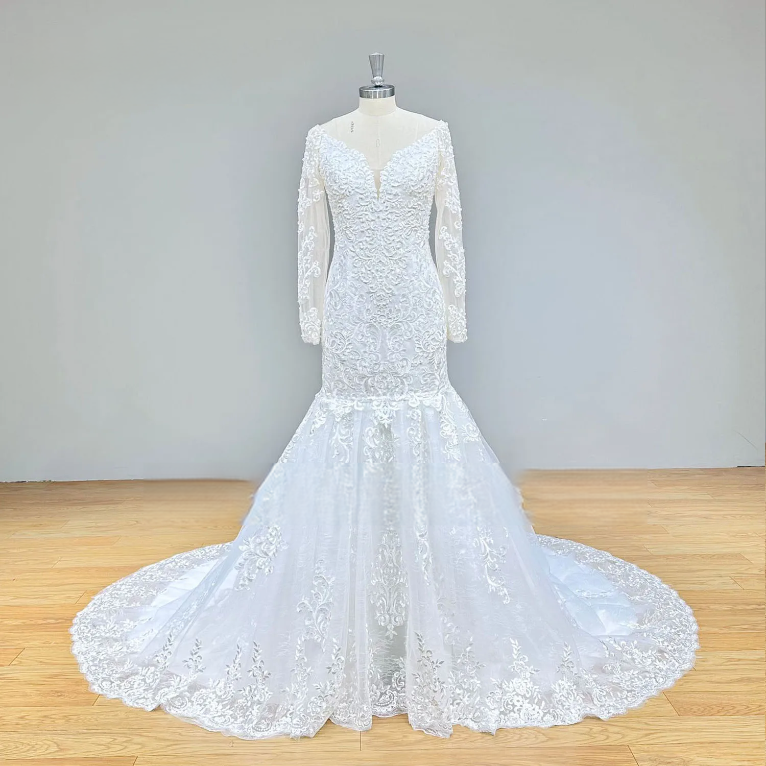 Full-length studio display of a pearl-encrusted lace mermaid wedding dress with long sleeves and an illusion sweetheart neckline.