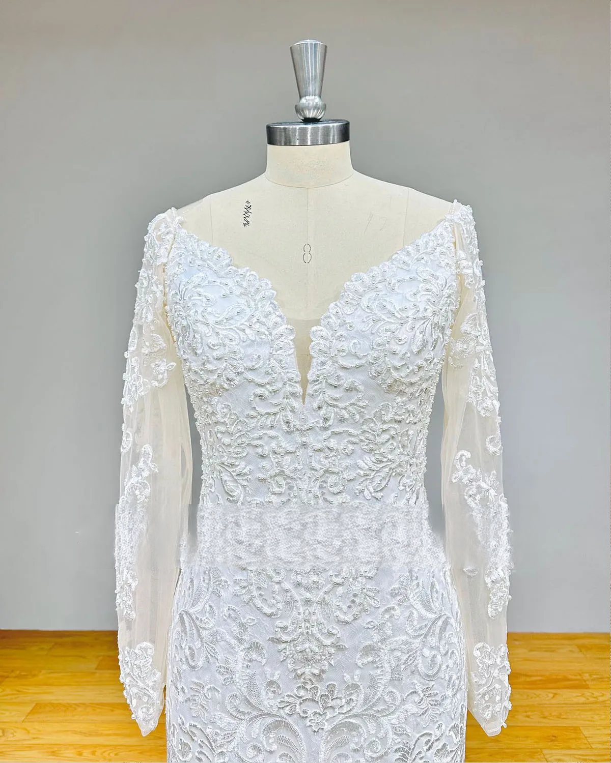 Close-up of the wedding dress bodice featuring a deep plunging sweetheart neckline and high-quality floral lace with hand-sewn pearls.
