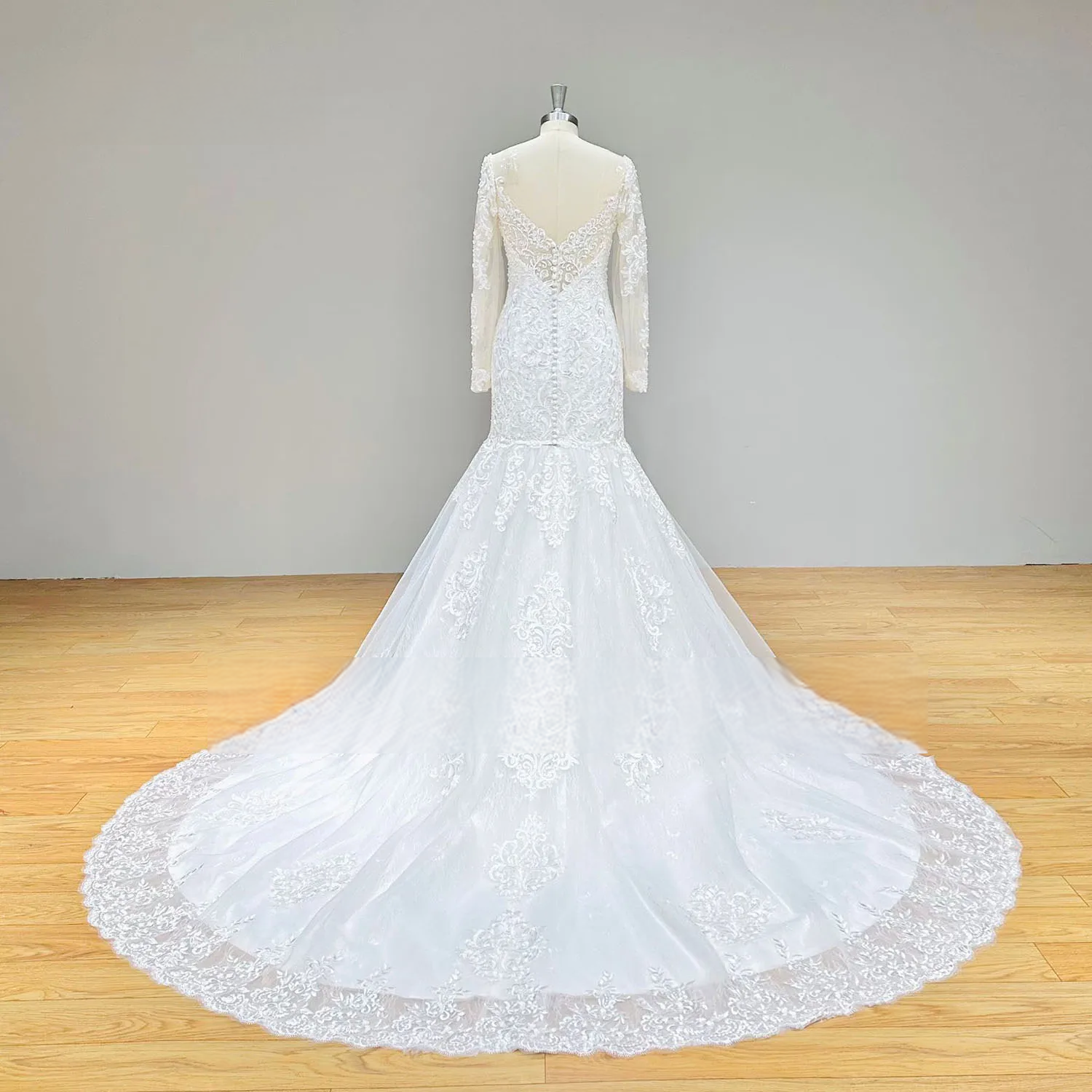 Full rear perspective of a lace mermaid bridal gown on a mannequin, showing the grand circular lace train and elegant backless silhouette.