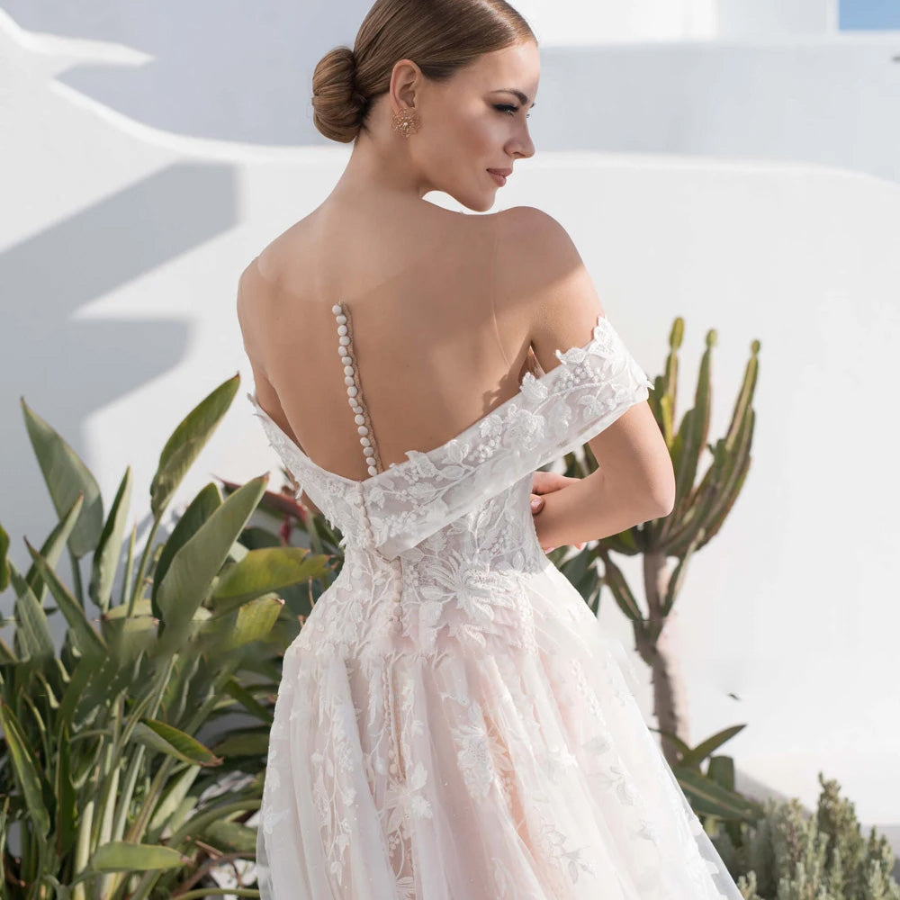Back view of a bride modeling a sweetheart lace A-line wedding dress, featuring an illusion back with button closures and detailed floral appliques.