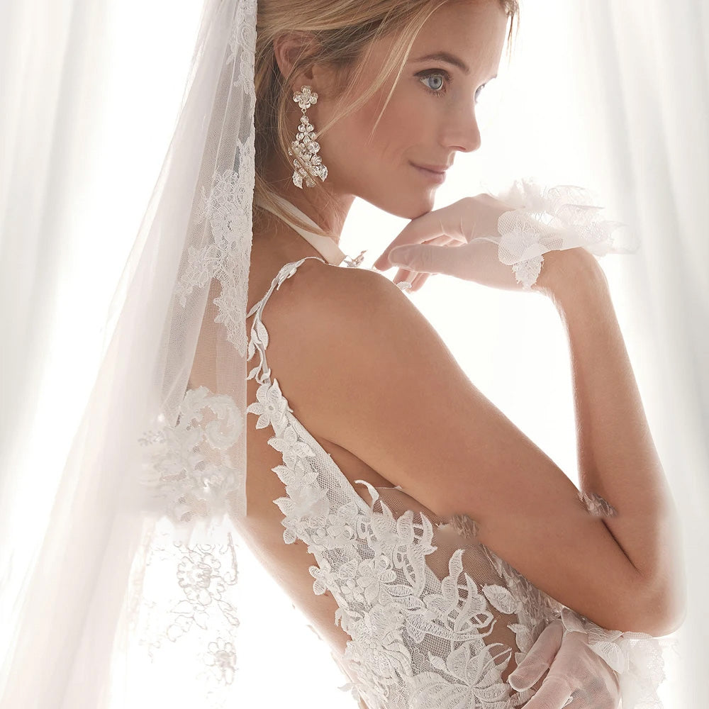 Side view of a boho-inspired A-line bridal gown with intricate lace appliques and spaghetti straps.