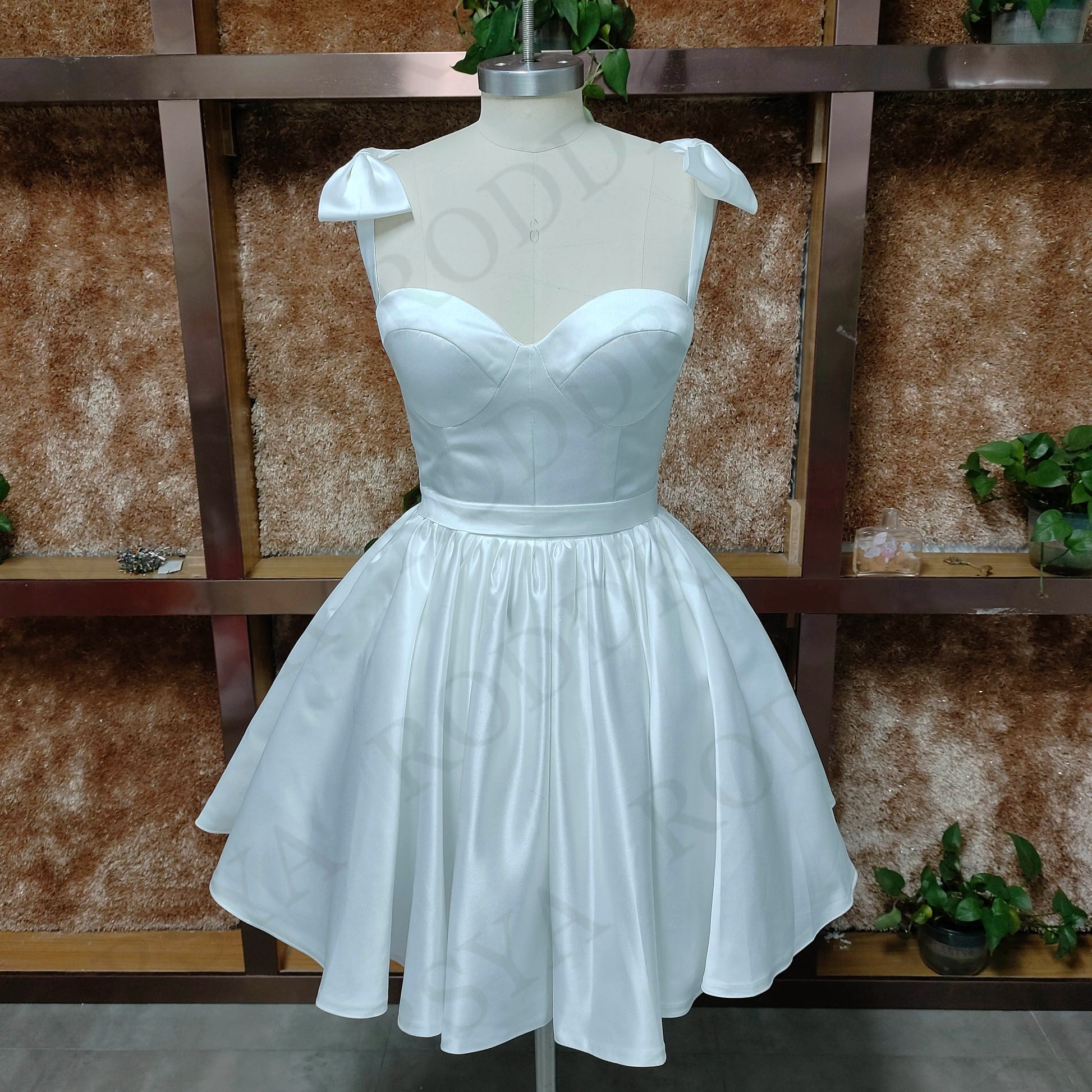 A mannequin displaying a romantic white sweetheart mini wedding dress with a clean A-line bodice and spaghetti strap detailing.