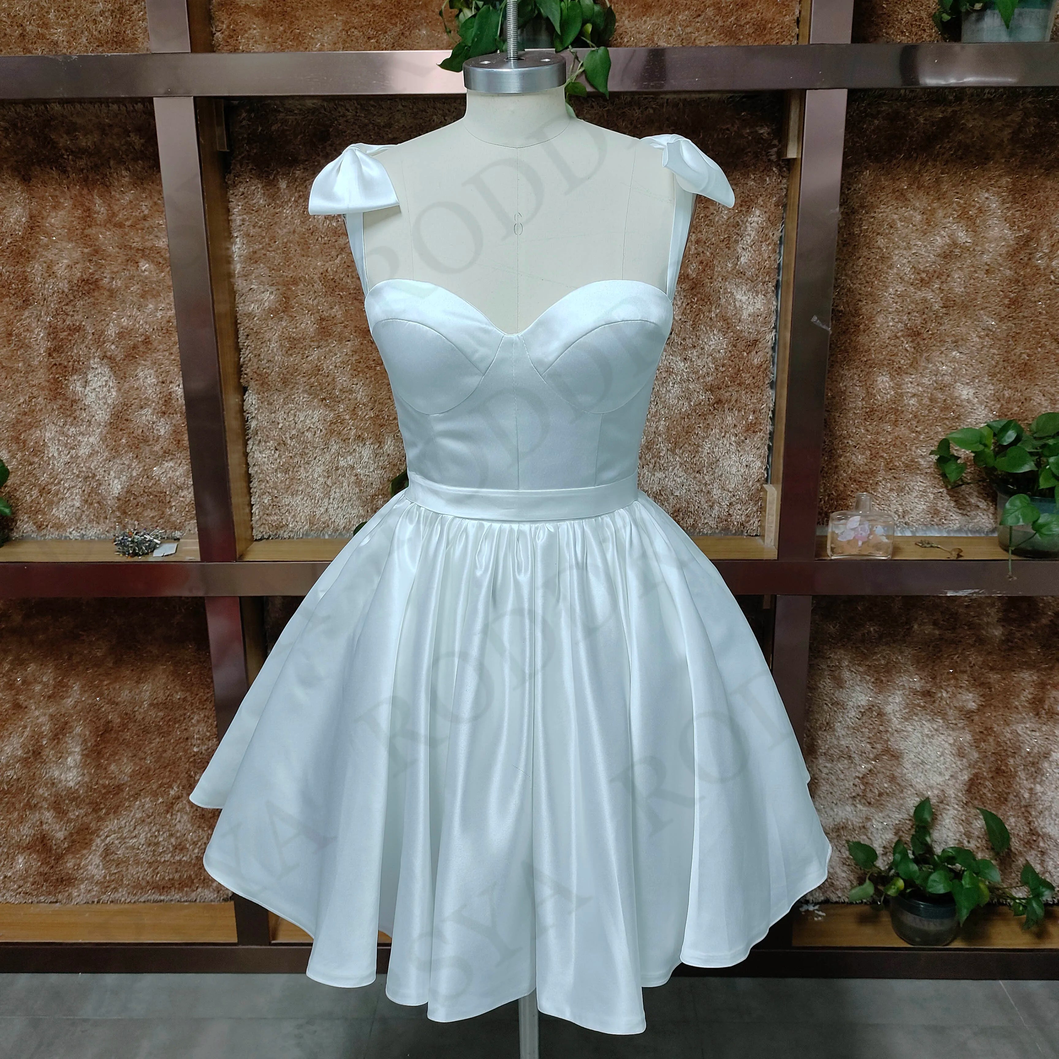 A mannequin displaying a romantic white sweetheart mini wedding dress with a clean A-line bodice and spaghetti strap detailing.