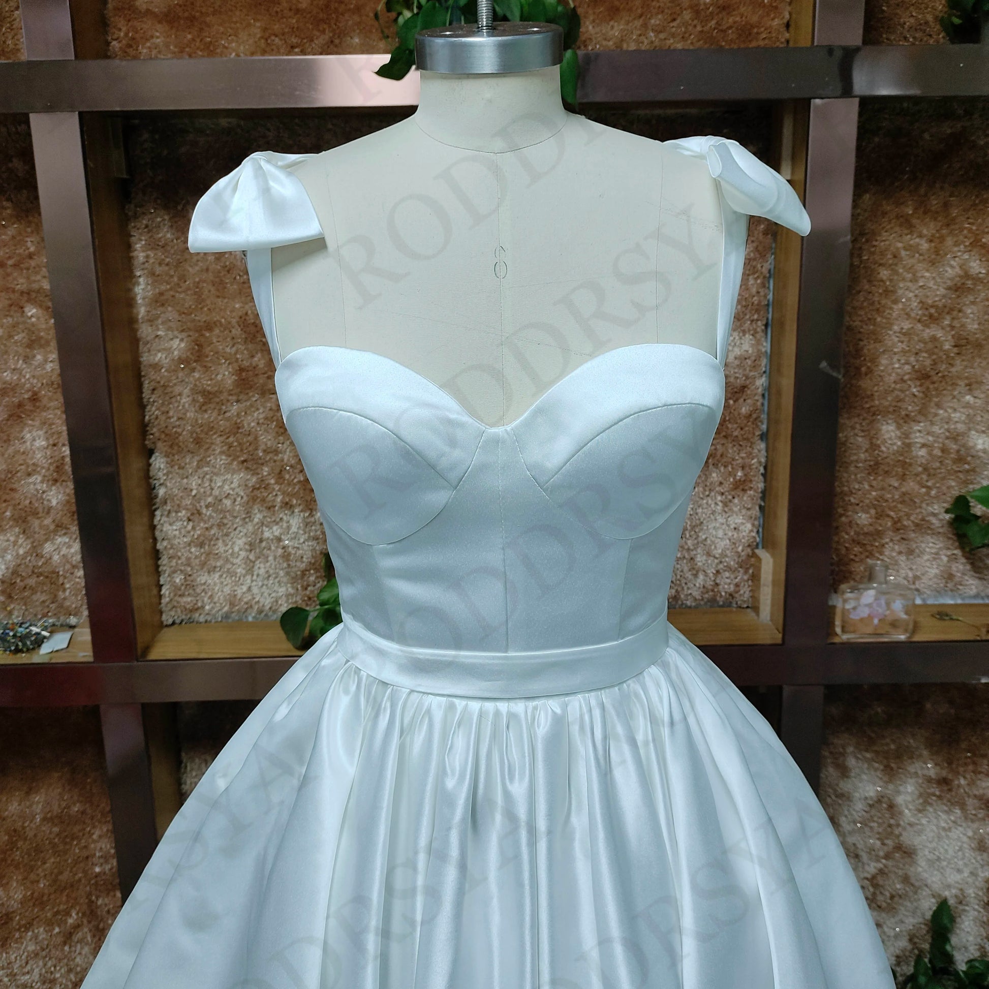 Detailed front view of the sweetheart bodice and spaghetti strap design on a short, elegant white bridal gown.