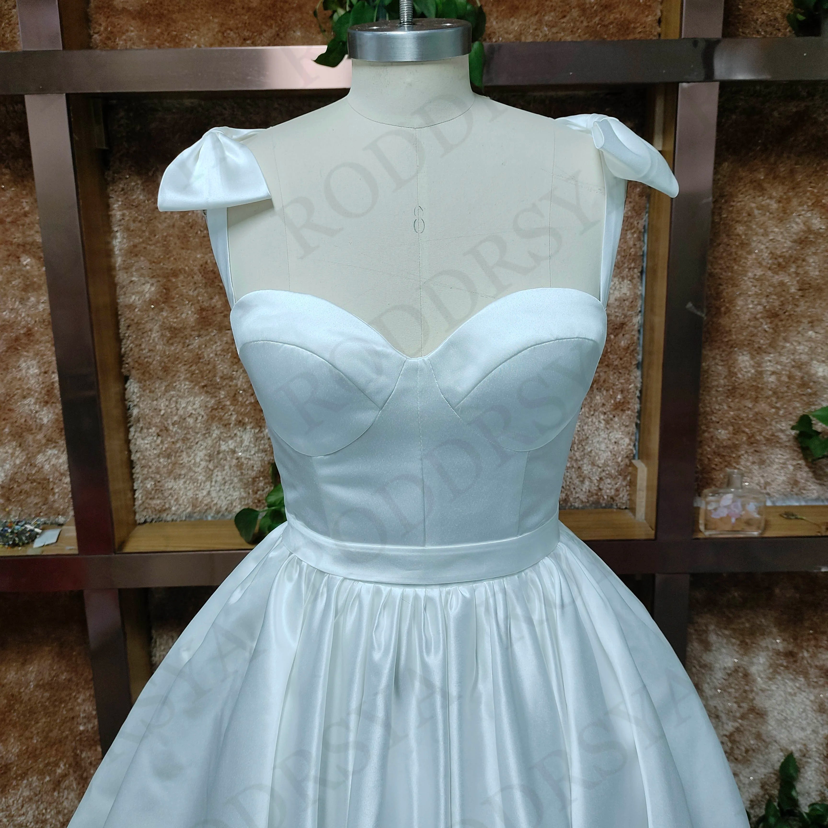 Detailed front view of the sweetheart bodice and spaghetti strap design on a short, elegant white bridal gown.