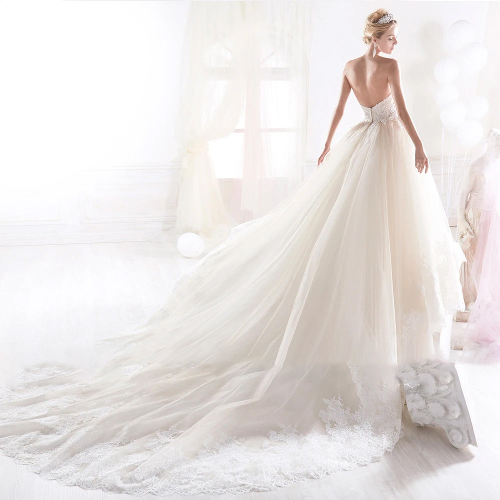 Back view of a sexy backless A-line bridal gown with delicate lace appliques and a dramatic court train.