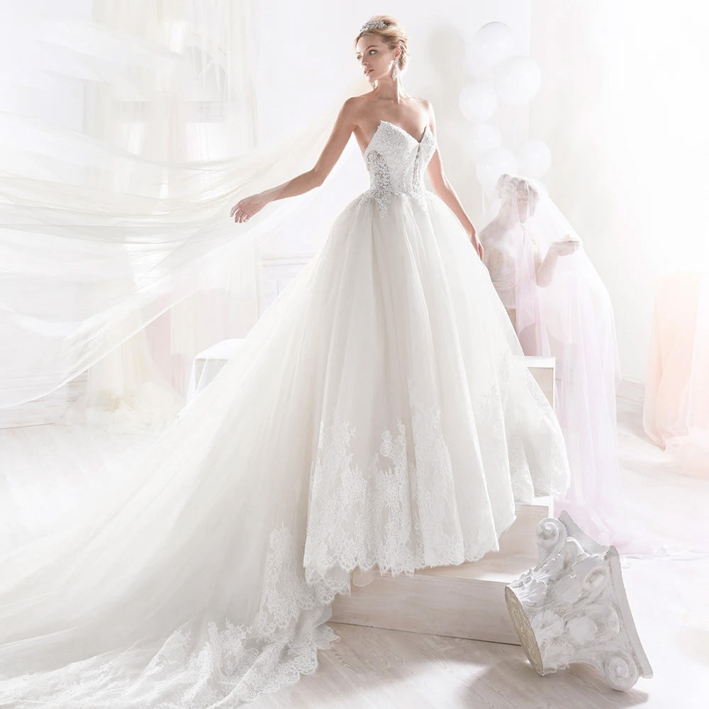Full-length view of a vintage-inspired A-line wedding dress with a dramatic court train and lace appliques.