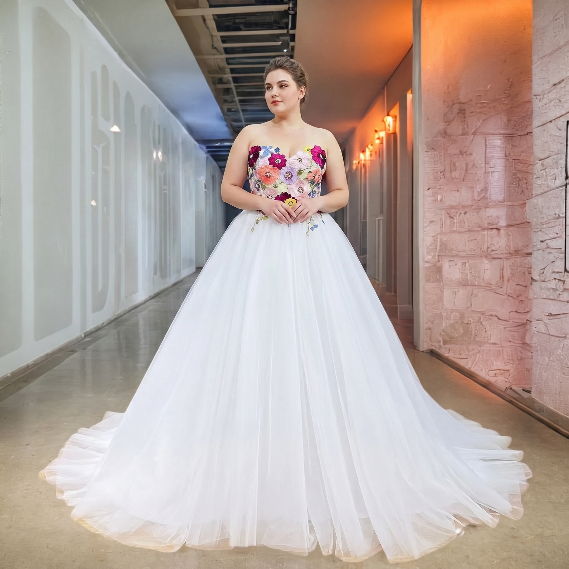 Full-length front perspective of a plus-size bride wearing a unique white ball gown wedding dress featuring a colorful floral embroidered corset and a voluminous tulle skirt.