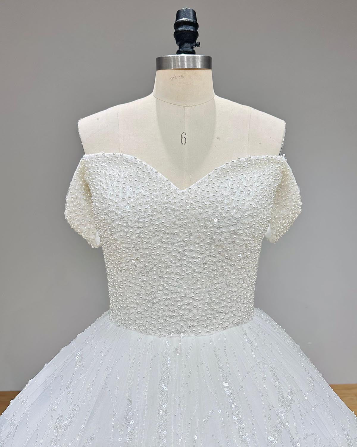 Close-up of the sweetheart neckline and intricate pearl-embellished bodice on a sparkly ball gown wedding dress.