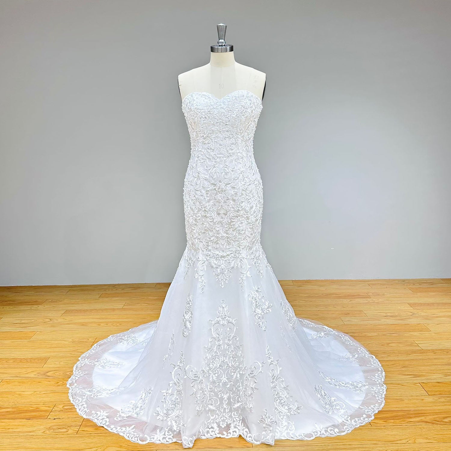 Classic sweetheart mermaid bridal dress featuring detailed floral lace embroidery and an elegant circular train on a mannequin.