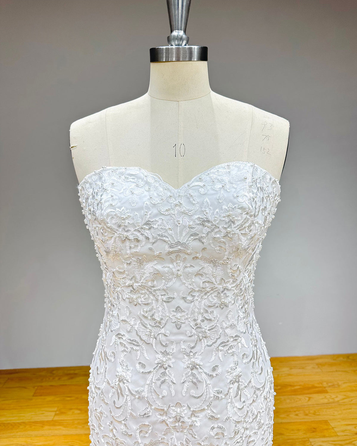 Close-up of a sweetheart bridal gown bodice highlighting the intricate floral lace patterns, delicate beadwork, and structured boning.