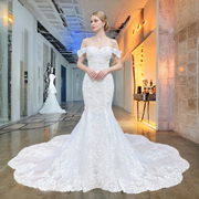 Elegant model posing in an off-the-shoulder sweetheart neck mermaid wedding dress, featuring rich lace appliques and a sweeping tulle train.