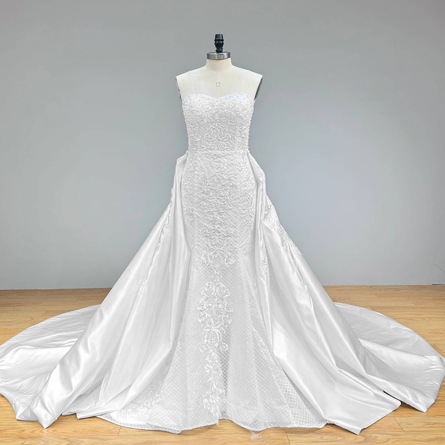 Wide full front studio view of an off-the-shoulder sweetheart neck mermaid wedding dress on a mannequin, capturing the stunning A-line illusion created by the attached sheer lace detachable train.
