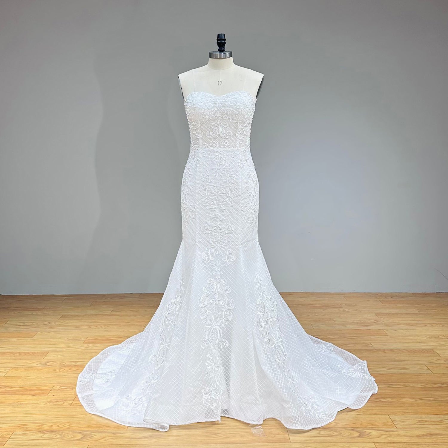Full back view of the fitted sweetheart neck mermaid wedding dress on a mannequin shown without the detachable train, displaying the elegant lace-up back and classic lace sweep train.