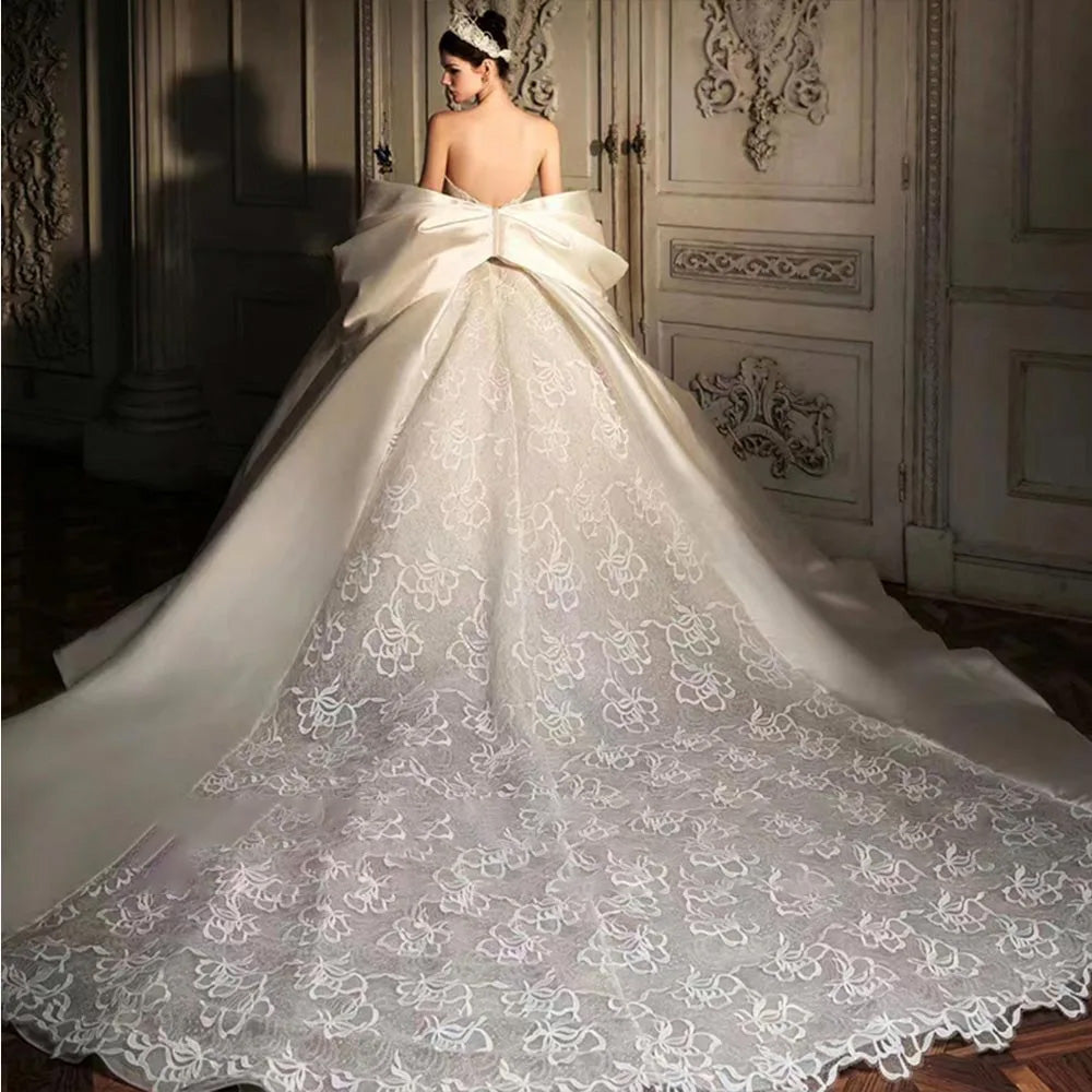Back view of a sophisticated satin wedding gown highlighting a large decorative bow and elegant silhouette.