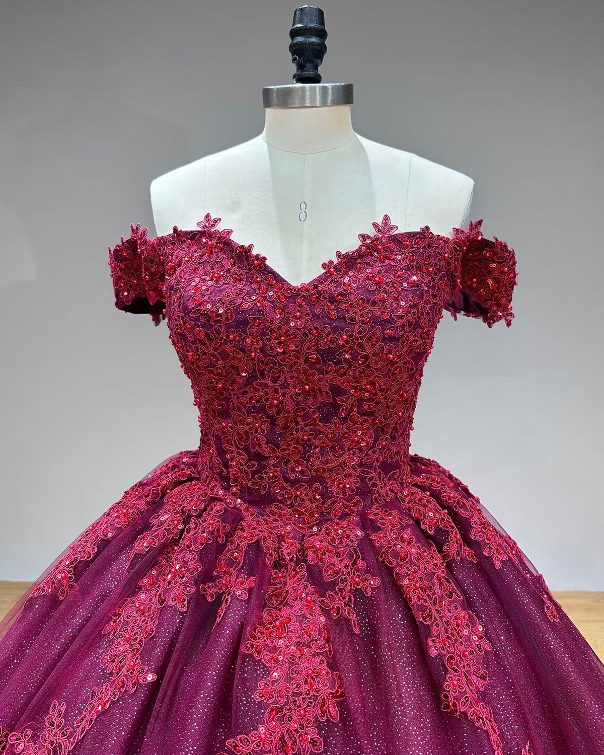 Detailed close-up front view of the sweetheart gown bodice highlighting the rich burgundy beading, shimmering sequins, and intricate floral lace appliques.