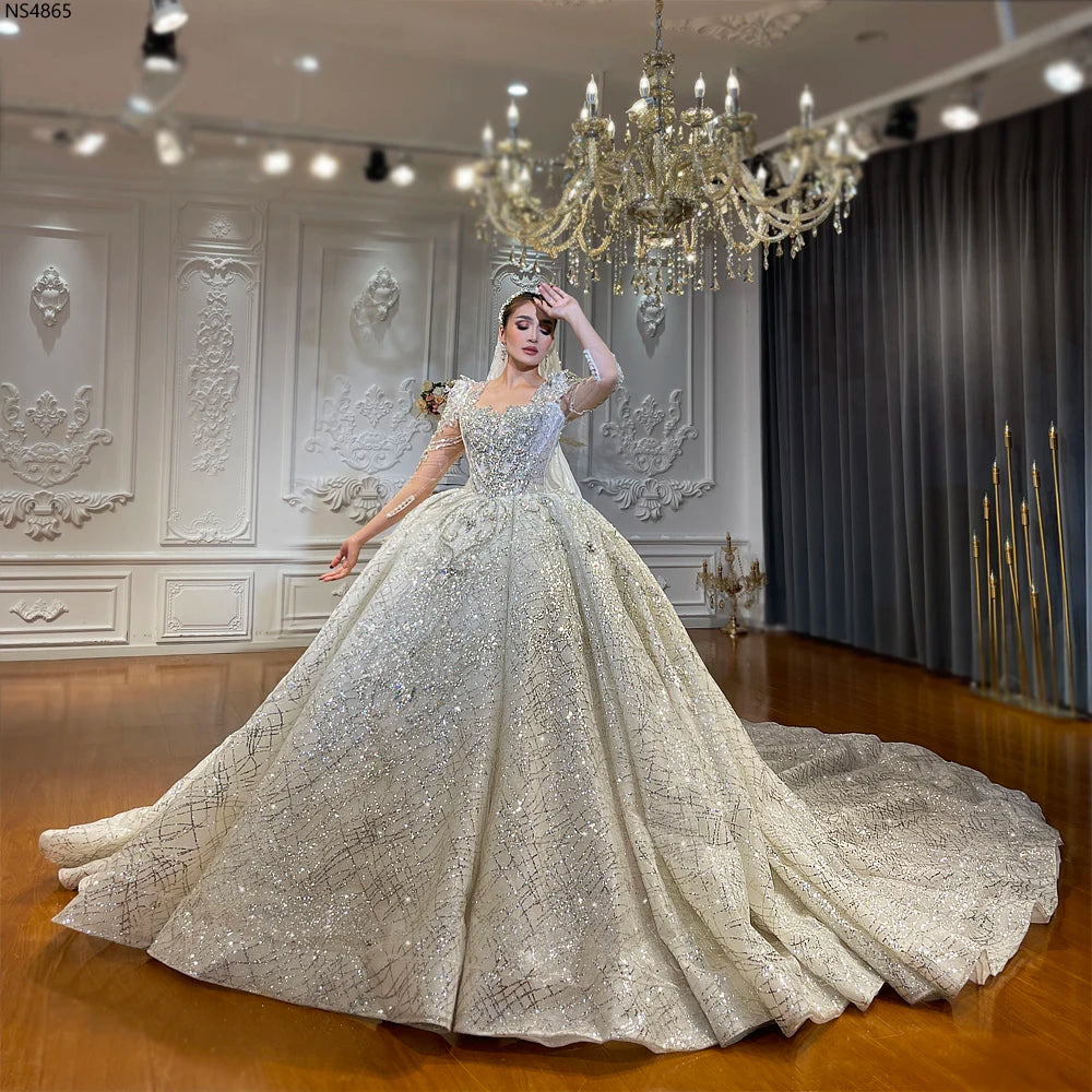 Full shot of a luxury sweetheart neckline wedding dress with long sleeves and a heavy beaded ball gown skirt, showcasing a grand royal silhouette and cathedral train.