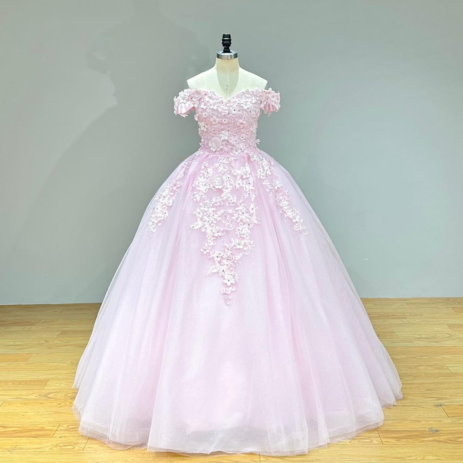 Elegant studio front view of a sweetheart pink dress on a mannequin, perfectly displaying the regal silhouette heavily embellished with pearls, crystals, and cascading 3D flowers.
