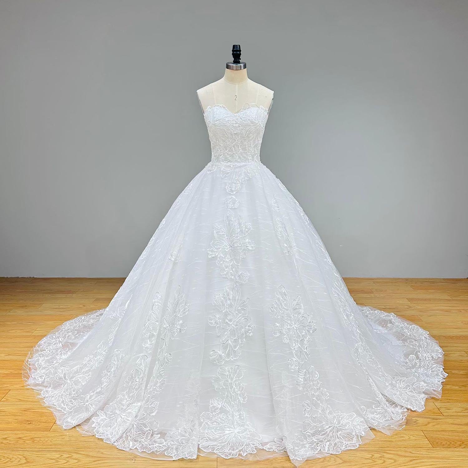 Close-up front bodice detail of a transparent sequined appliques ball gown wedding dress on a mannequin, emphasizing the sheer sweetheart neckline, intricate sparkling beading, and thin spaghetti straps.