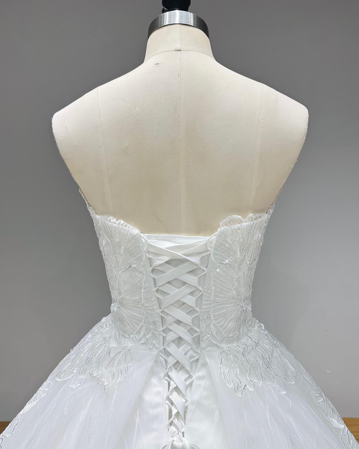 Classic full front studio view of a transparent sequined appliques ball gown wedding dress on a mannequin, capturing the perfectly fitted bodice and beautifully draped, voluminous sparkling skirt.