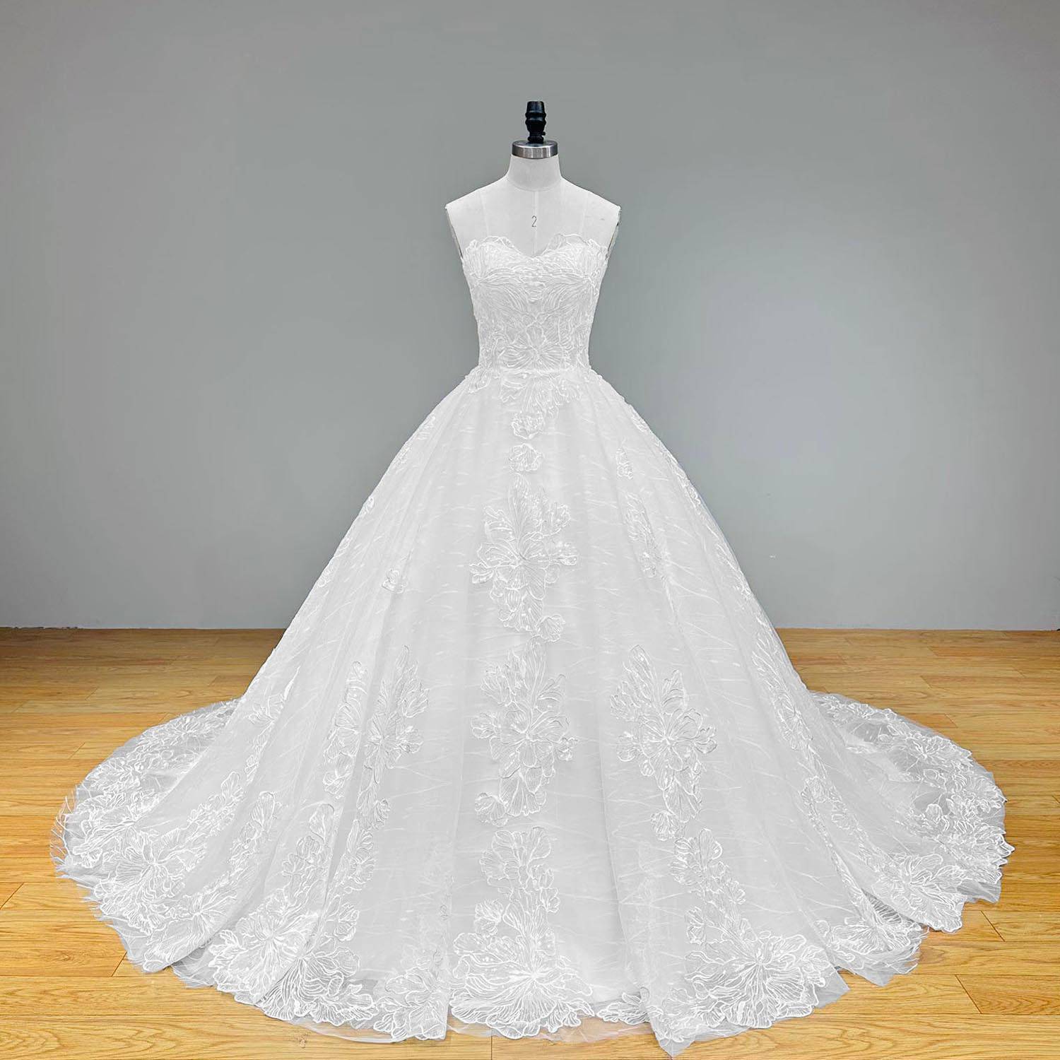 Wide back view of a shimmering transparent sequined appliques ball gown wedding dress on a mannequin, highlighting the exquisite lace-up back closure and expansive glittering train spreading across the floor.