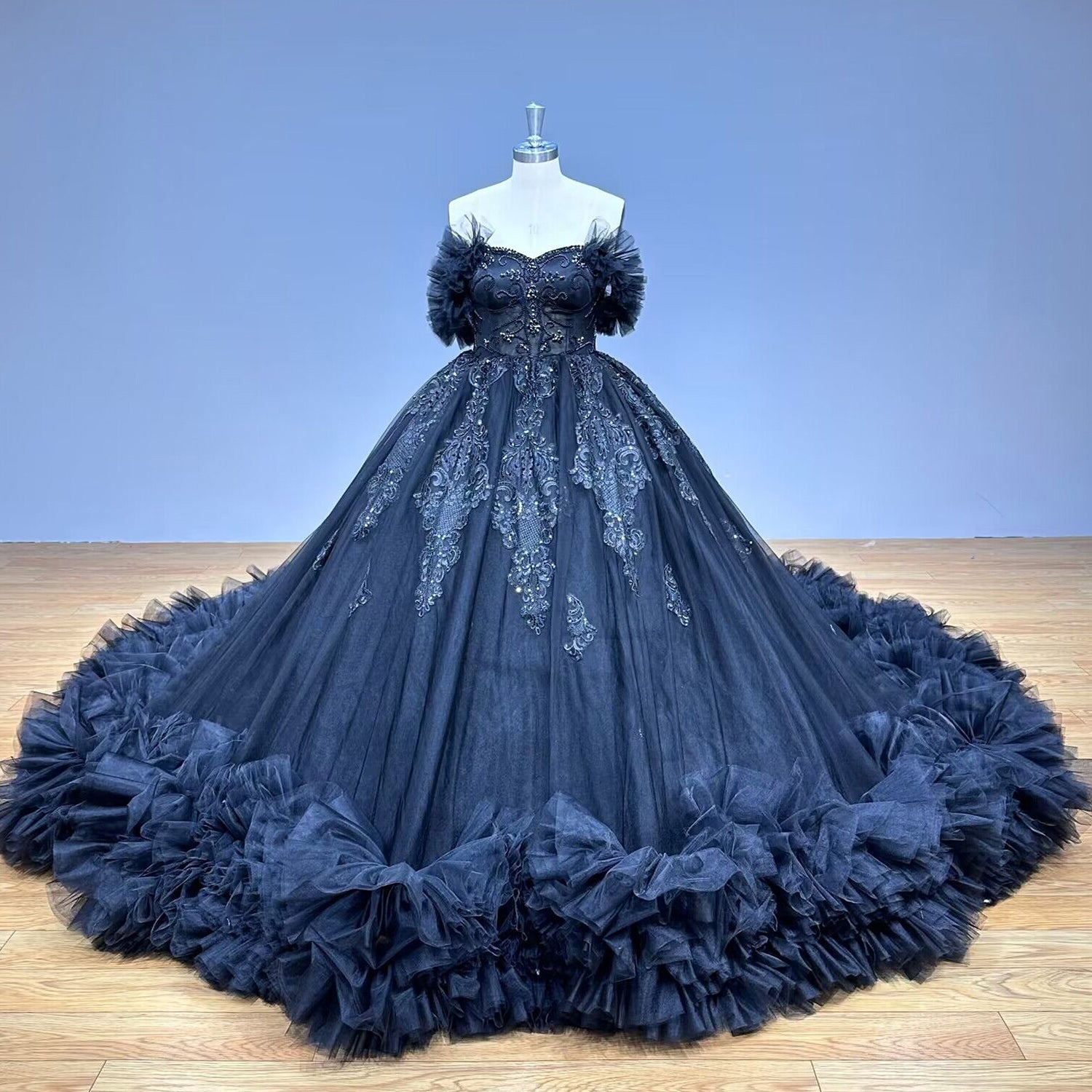 Classic tulle ball gown wedding dress with an off-the-shoulder sweetheart neckline displayed on a mannequin in a modern bridal boutique hallway.