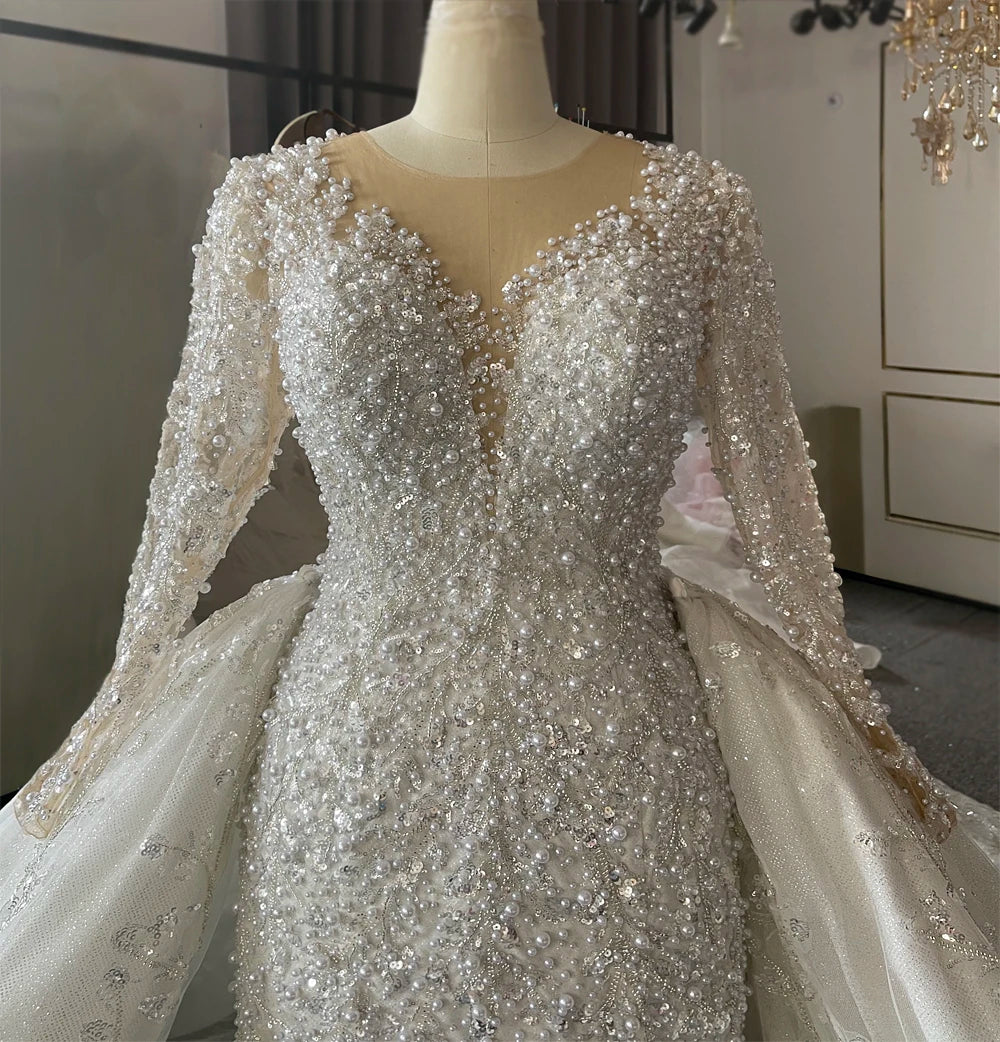 Rear perspective of the mermaid bridal gown on a mannequin, showcasing the elegant lace-up corset back and the transition to the sparkling detachable cathedral train.