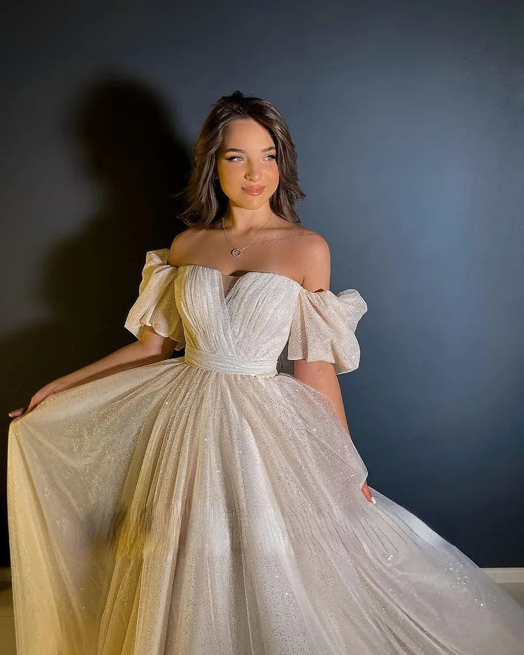 A bride wearing a glamorous off-the-shoulder princess wedding dress with a dramatic detachable train and shimmering fabric.
