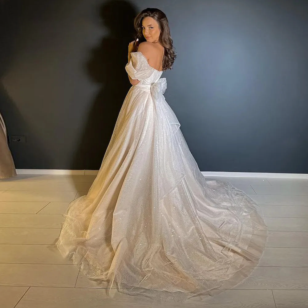 A full-length view of a princess-style wedding gown with a voluminous, sparkling detachable train and intricate details.