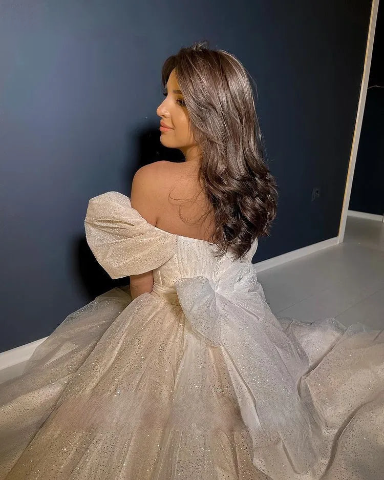 A close-up view from behind showing the back detailing of a princess wedding dress with a large decorative bow and detachable train.
