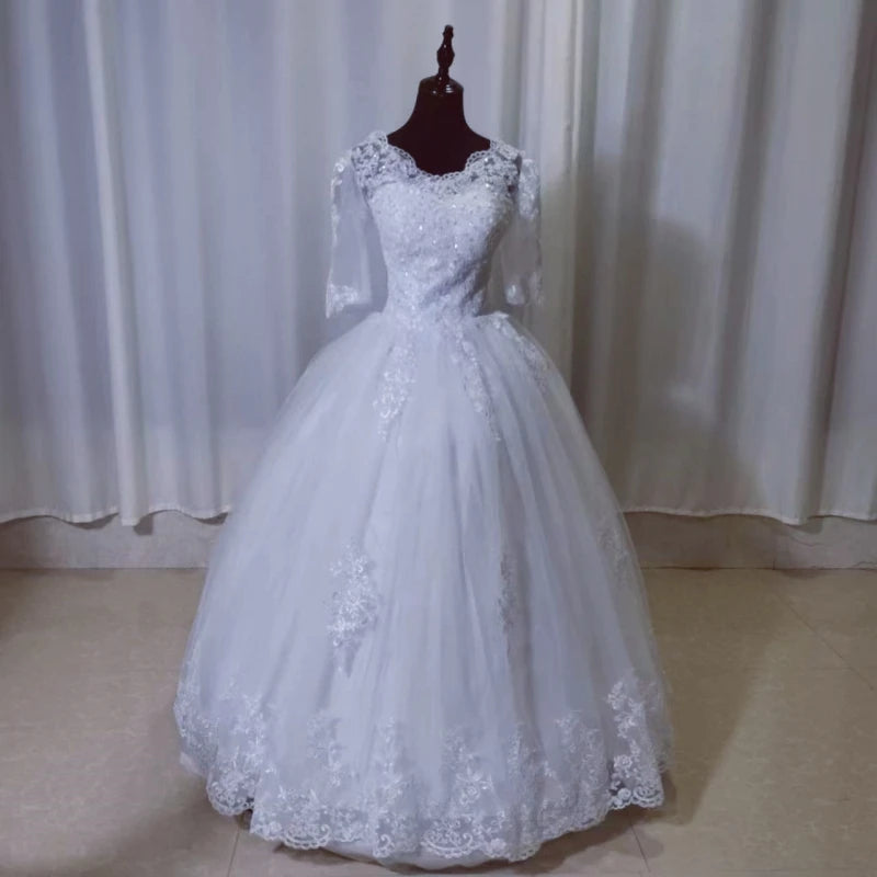 Plus size white wedding gown with full sleeves and a long train, displayed on a mannequin in a studio setting.