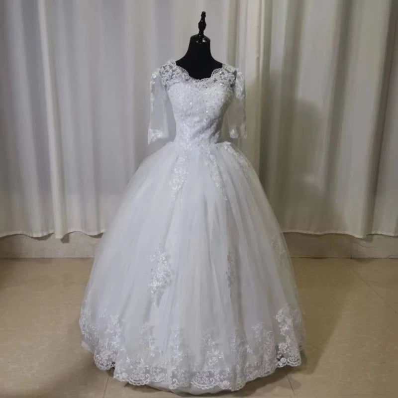 Plus size white wedding gown with full sleeves and a long train, displayed on a mannequin in a studio setting.