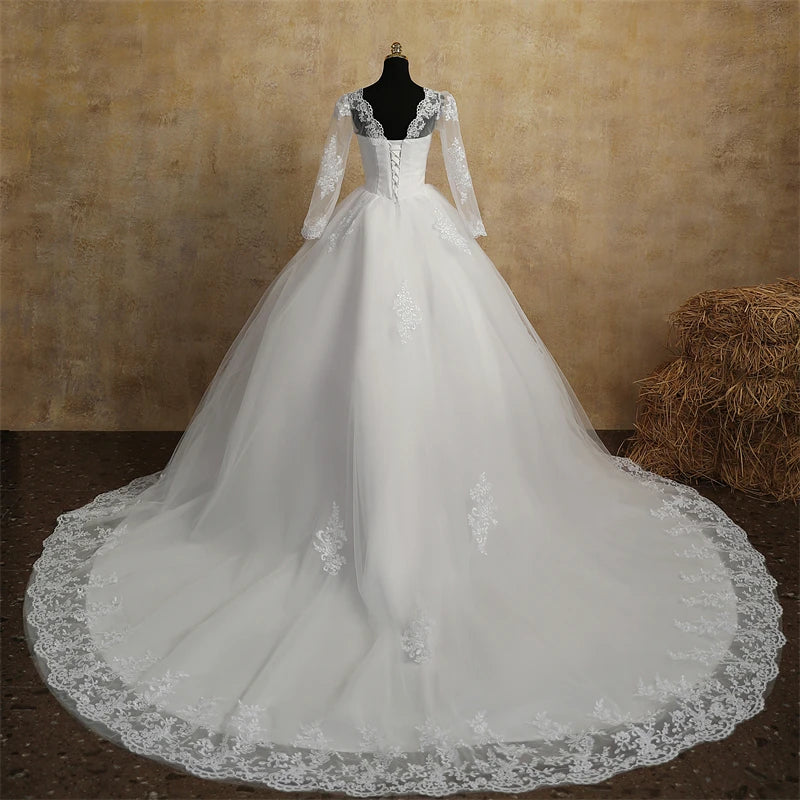 Elegant white bridal gown with full sleeves and intricate lace details, viewed from the back to highlight the long, ornate lace train.