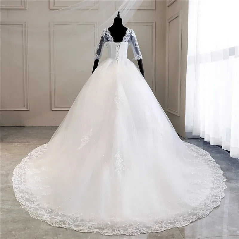 Close-up front view of a long-sleeve, V-neck wedding dress, highlighting the fine lace work on the bodice and full skirt.